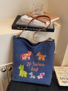 Blue canvas tote bag with colorful animal embroidery and brown leather shoulder straps