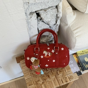 Detail of red pillow bag with white star prints and rocking horse embroidery on a chair