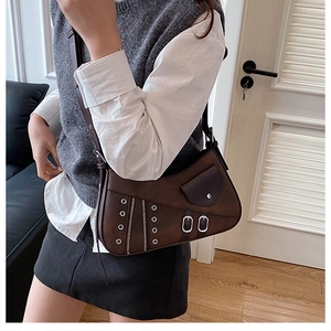 Macro shot of dark brown saddle bag featuring silver metal eyelets and zipper details