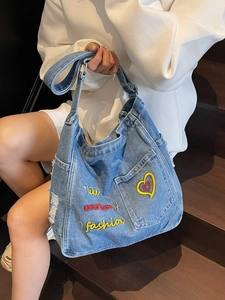 Denim tote bag with heart embroidery and multiple pockets shown in lifestyle setting