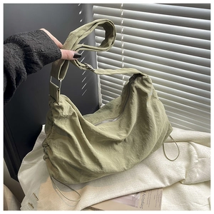 Détail de la bandoulière réglable et du design à cordon sur un sac hobo en nylon vert
