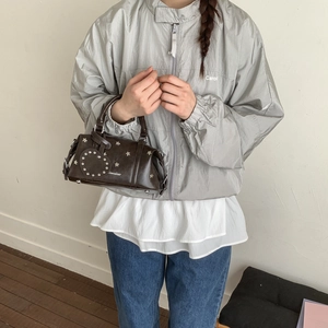Detail der dunklen Leder-Pillow-Bag mit Sternnieten und Herzanhänger am Outfit