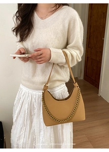 Detail der kamelfarbenen Halbmond-Ledertasche mit goldener Kette am Model