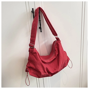 Détail du sac bandoulière en nylon rouge imperméable avec cordon et boucle en métal