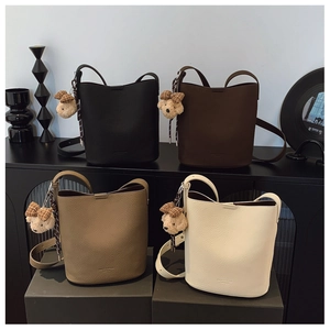 Detail view of retro bucket bags in four colors with adjustable straps and teddy charms