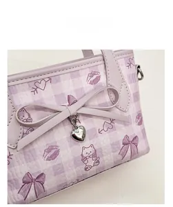 Detail of purple plaid bag with cat print, leather bow, and heart metal pendant charm