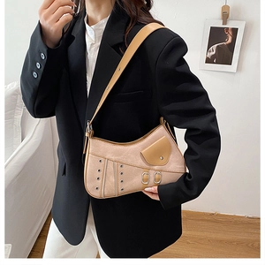 Detail of khaki suede saddle bag with metal hardware and buckles worn by model