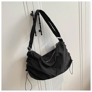 Détail du sac bandoulière en nylon imperméable avec texture froncée et anneau argenté