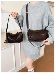 Detail of dark brown crescent leather bags in two sizes with gold metal hardware