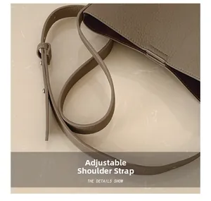 Detail of brown lychee grain leather bag showing adjustable strap with metal buckle