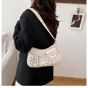 Detail view of beige saddle bag with metal eyelets and adjustable strap on a model