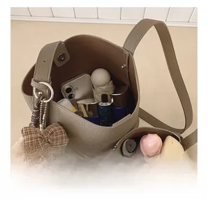 Detail view of khaki bucket bag interior capacity with inner pouch and bear charm