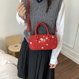 Detail view of red Boston bag with star patterns and rocking horse patch worn on shoulder
