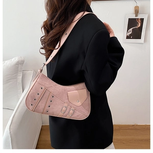Detail of pink faux-suede underarm bag featuring metallic rivets and decorative zippers