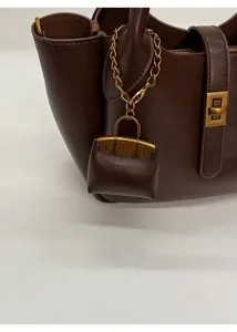 Detail of dark brown leather handbag with miniature bag charm and gold metal hardware