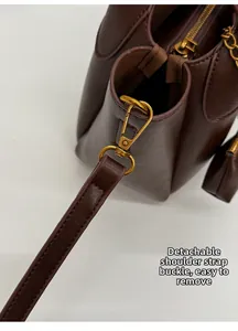 Detail of the vintage gold hardware buckle on a dark brown leather shoulder bag