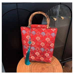 Detail of red jacquard handbag with wave patterns, bamboo handles and blue tassel decoration