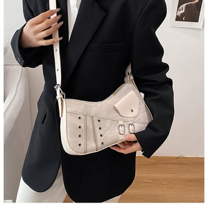 Detailed view of beige faux leather handbag with motorcycle style metal hardware and buckles