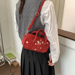 Detail of red crossbody bag with star pattern and embroidered rocking horse on a model