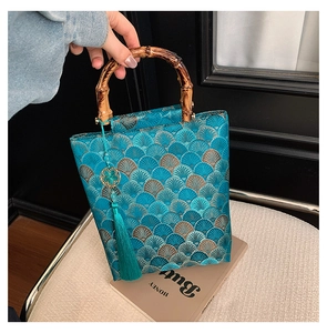 Detail of teal jacquard handbag with gold fan patterns and carbonized bamboo handles