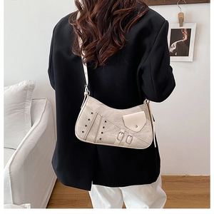 Detail view of beige textured underarm bag with metal eyelets and decorative zipper