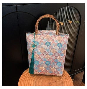 Detail of embroidered tote bag with bamboo handle and elegant green tassel pendant