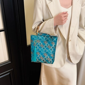 Detail of Chinese embroidery handbag with bamboo handle and blue tassel on silk fabric