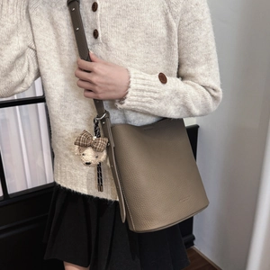 Detail of khaki bucket bag featuring lychee grain leather and cute plush bear charm