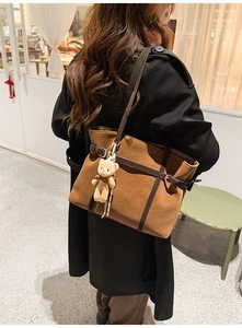 Brown large capacity tote bag with bear charm shown on model in black wool coat