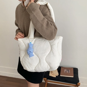 Minimalist white quilted puffer tote bag for women with wave stitching and blue bow pendant