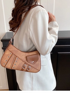 Vintage brown leather underarm bag with metal rivets and decorative zippers on model