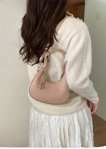 Detail of light pink pebble leather crescent shoulder bag with silver buckle and adjustable strap