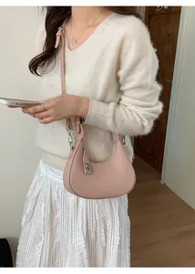 Close-up of pink crescent shoulder bag in lychee pattern leather with silver metal buckle