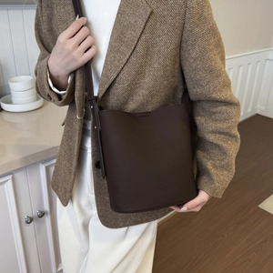 Close-up of a vintage dark brown bucket bag with lychee texture and thin shoulder strap