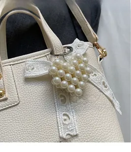 Close-up of heart-shaped pearl charm with lace detail on a textured white bucket bag
