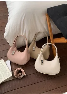 Close-up of hobo handbags in pink, beige, and white with textured lychee leather and silver locks