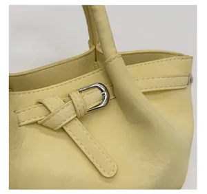 Close-up of pale yellow bucket bag showing wrinkled leather texture and silver buckle