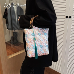 Detail of Chinese embroidery bucket bag featuring a bamboo handle and long blue tassel