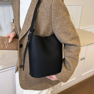 Detail view of black pebble leather bucket bag with slim adjustable strap on model