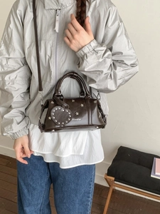 Braune Retro-Pillow-Bag aus PU-Leder mit silbernen Sternnieten und Herzanhänger am Model