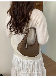 Rear view of a model wearing the brown textured leather crescent bag in a cozy room