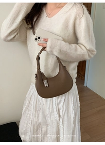 Detail of brown pebbled leather crescent hobo bag with silver metallic buckle and clasp