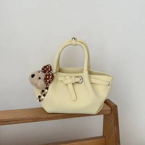 Detail of yellow PU leather bucket bag with brown teddy bear charm and belt buckle decor