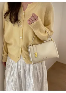 Detailed macro view of cream lychee leather texture and golden metal twist lock on handbag