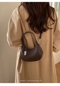 Detail of dark brown lychee leather hobo bag featuring a silver metal rotating clasp