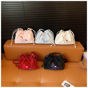 Detail of five colorful drawstring bucket bags with cartoon horse patch on a leather sofa