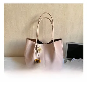 Détail du cabas en cuir rose avec pendentif fleur tissée et pompon en perles de bois