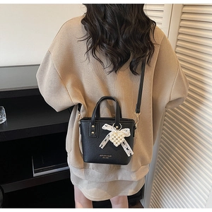 Litchi texture leather tote bag with lace bow and pearl charm shown on model's back