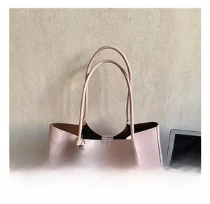 Détail du sac cabas minimaliste rose montrant les poignées confortables et le pendentif