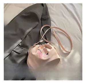 Detail of pink drawstring bucket bag featuring a soft plush animal embroidery and leather strap